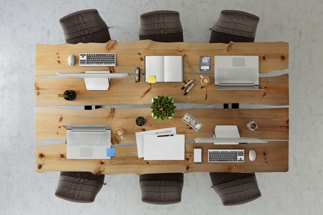 A wooden table with several computers on it.